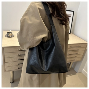 Detailed side view of black vintage faux leather tote bag with soft pleated texture and wide strap