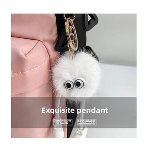 Detail of white fluffy monster charm with large eyes on a pink nylon backpack zipper