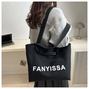Détail du sac cabas en toile noire avec lettrage blanc et large bandoulière confortable