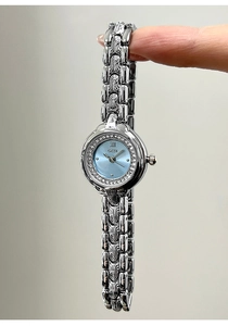 Close-up of luxury silver watch with light blue dial and rhinestone-inlaid bezel