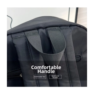 Detail of reinforced padded handle and wide shoulder straps on a black nylon backpack