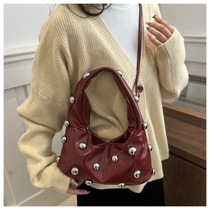 Detail of red glossy half-moon bag with silver metallic sphere rivets and pleat textures