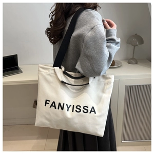 Side view of large canvas tote bag with FANYISSA print and black wide shoulder strap