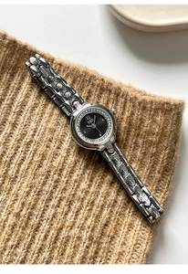 Macro detail of GEDI watch with black dial and silver relief pattern band on knit fabric