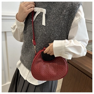 Detail of dark red crescent bag featuring woven honeycomb texture and gold metal hardware