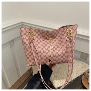 Detailed shot of pink monogrammed tote bag with gold chain strap and deer charm