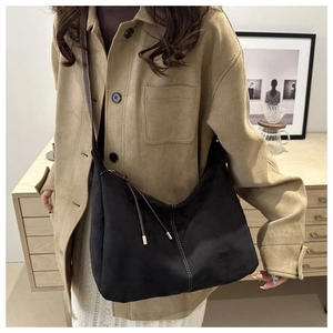 Detail of black suede tote bag with contrast white stitching and brown shoulder strap