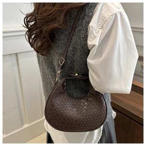 Detail of dark brown woven texture and gold clasp on the crescent shoulder bag