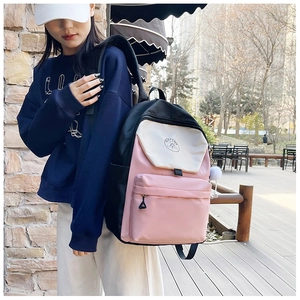 Detail of color-block backpack with white plush ball charm and logo on a terrace