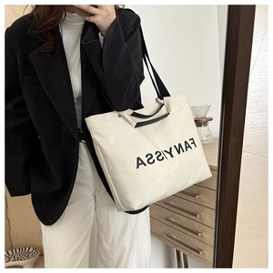 Detail of canvas tote bag with black handles and metal rivet fasteners for durability
