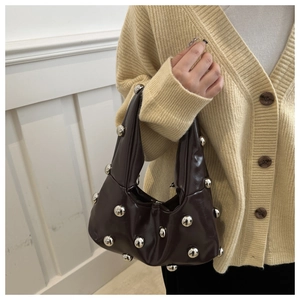 Detail of dark brown glossy patent leather hobo bag featuring large silver metal studs