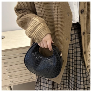 Détail du sac croissant noir tissé avec texture en cuir et anneau en métal doré