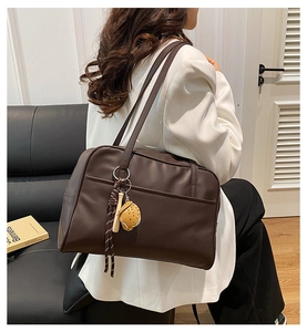 Deep brown oversized PU tote bag with a sporty charm pendant on professional model