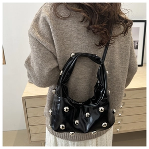 Detail of black patent leather underarm bag with large silver round metallic studs