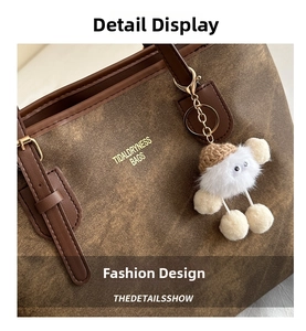 Detail of coffee tote bag with vintage texture and cute white plush charm on golden ring
