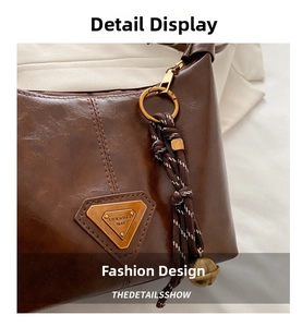 Detail of dark brown faux leather bag with triangular metal logo and woven rope zipper pull