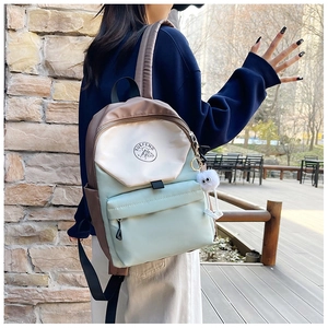 Detail of color-block nylon backpack featuring mountain logo and white plush pendant
