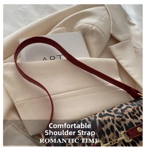 Detail of leopard print tote featuring wine red leather strap and metallic buckle