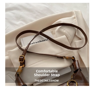 Close-up of adjustable strap with bronze metal buckle on dark brown leather bag