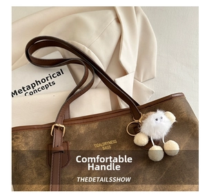 Close-up of retro brown textured tote bag featuring leather handles and a plush charm