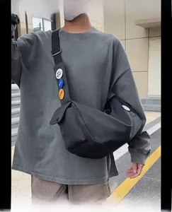 Outdoor shot of a black nylon messenger bag featuring decorative badges on the shoulder strap
