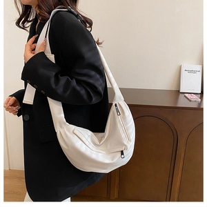 Detail of white crescent crossbody bag with black zipper contrast and leather texture