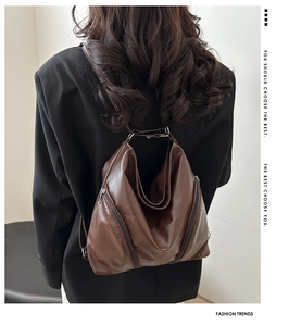 Detail of dark brown leather backpack featuring stylish wrinkles and zip accents on black blazer