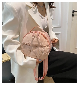 Close-up of pink quilted round bag featuring bow embroidery and dual zippers
