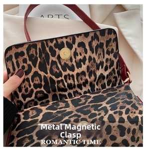 Detail of the golden magnetic clasp closure on a leopard print hobo bag with red strap