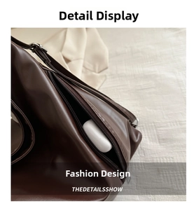 Detail view of leather tote with side zipper pocket holding a wireless earbud case