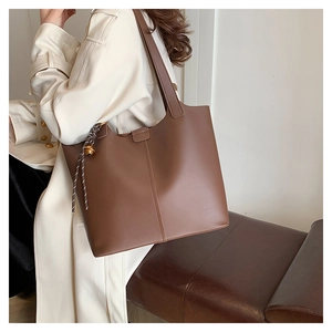 Détail macro du sac cabas en cuir marron avec grande capacité et accessoire de clochette
