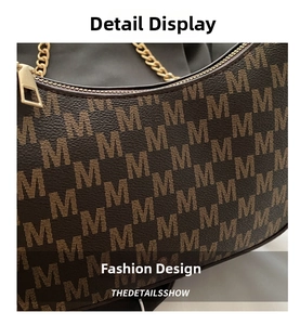 Detail of brown monogram shoulder bag featuring leather texture and gold chain link zipper