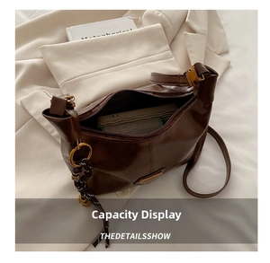 Interior view showing the large capacity of a dark brown crescent bag with metal logo