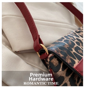 Detail of leopard print handbag with red leather strap and golden D-ring hardware