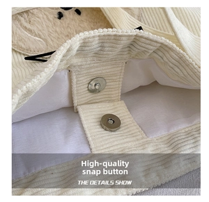 Detail of metal magnetic buckle and soft corduroy texture on white tote bag