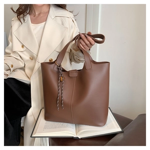 Gros plan sur un cabas vintage marron avec nœud rayé sur un trench-coat beige élégant