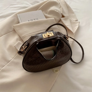 Sac à main croissant marron foncé avec texture tressée et détails en métal doré