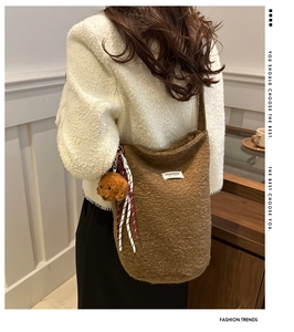 Detail of soft brown fleece bucket bag texture with a cute puppy plush keychain charm