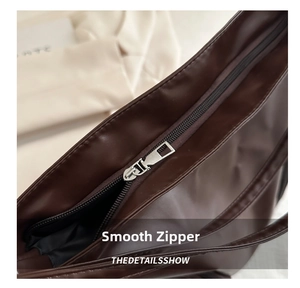Close-up of smooth metal zipper detail on deep brown vintage PU leather tote bag