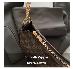 Detail of smooth golden zipper and monogram print on vintage crescent bag with chain strap