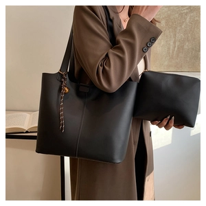 Détail du sac cabas en cuir mat noir et sa pochette avec gland tressé et anneau doré