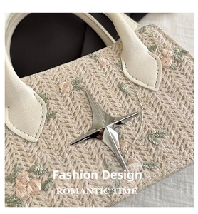Close-up of beige straw handbag with floral embroidery and silver star ornament detail