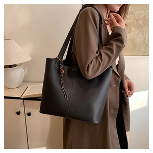 Grand sac fourre-tout noir avec breloque tressée, porté avec un blazer marron chic
