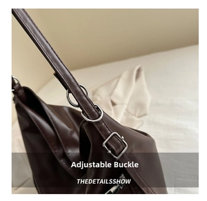 Close-up of adjustable strap with silver buckle and metal rings on brown leather bag