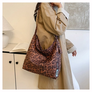 Detail showing high-capacity leopard print faux suede tote bag with woven brand label