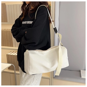 Détail latéral d'un grand sac bandoulière en nylon blanc avec sangle réglable sur modèle