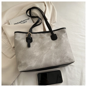 Detail of grey marbled tote bag with black leather straps and gold metal buckles