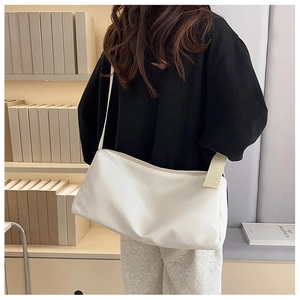 Détail de la bandoulière large beige et du zip fluide sur le sac messager blanc