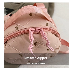 Detailed macro view of smooth dual-direction zippers on a pink quilted bow handbag