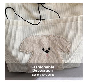 Detail show of white corduroy tote bag featuring plush puppy applique and drawstring